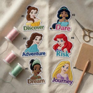 May include: Six colorful embroidered patches featuring cartoon princesses with text: Discover, Dare, Adventure, Risk, Dream, and Journey. The patches are on a cream-colored fabric, with spools of thread and sewing tools.