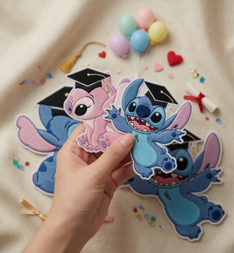May include: Embroidered patches featuring the characters Stitch and Angel from Lilo & Stitch, wearing graduation caps. The patches are blue and pink, with black caps. Small balloons, confetti, and a diploma are in the background.