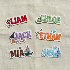 May include: Embroidered name patches in various colors. Names include Liam, Chloe, Jack, Ethan, Mia, and Ava. Each patch features a unique design element, such as a dragon, frog, or sailboat. These patches are ideal for personalizing clothing or accessories.