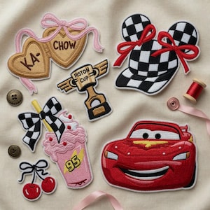 May include: Embroidered patches with various designs. Includes a red race car, a checkered milkshake, a trophy, a checkered hat with bows, a pair of cherries, and heart-shaped patches with text.