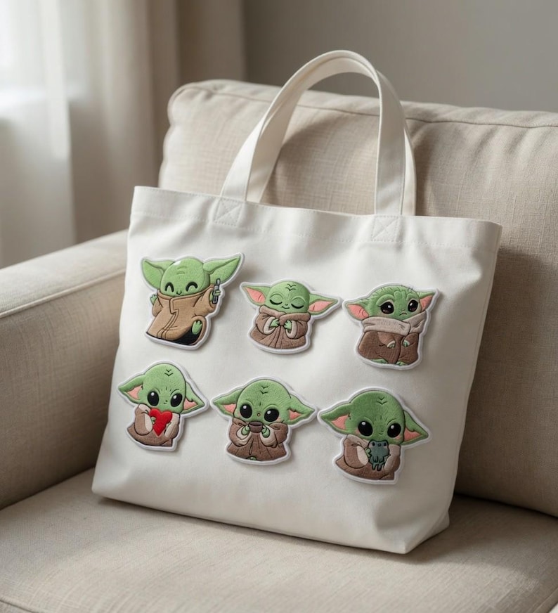 May include: White canvas tote bag with seven embroidered patches of a green alien character. The patches show the character in different poses, wearing a brown cloak and holding objects. The bag has two white handles and is on a beige sofa.
