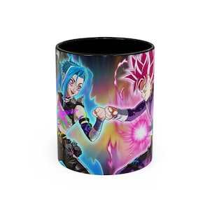Puede incluir: Taza de café de cerámica en blanco y negro con dos personajes animados chocando los puños. Un personaje tiene el pelo azul y el otro rosa. El interior de la taza es negro.