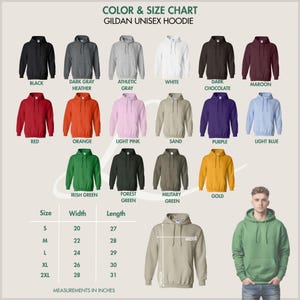 Pode incluir: Tabela de cores e tamanhos para hoodies unissexo Gildan. A tabela mostra v&aacute;rias cores de hoodies, incluindo preto, cinzento, branco, vermelho, laranja e verde. As medidas s&atilde;o em polegadas, com tamanhos de S a 2XL. Uma pessoa est&aacute; a usar um hoodie verde.