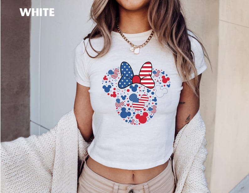 May include: White t-shirt with a Minnie Mouse design in red, white, and blue. The design includes a bow, hearts, and Mickey Mouse silhouettes. The word "WHITE" is in the upper left corner of the image.