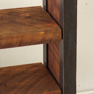 May include: A wooden shelf unit with two shelves, supported by a black metal frame. The shelves are made of reclaimed wood with a natural brown finish.