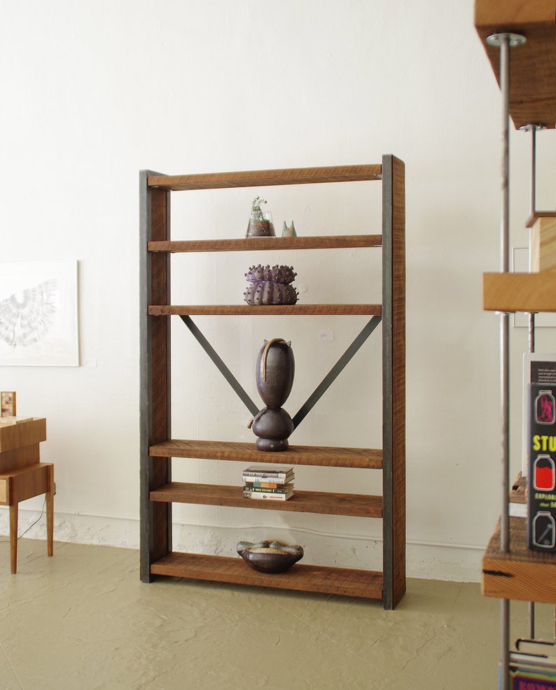 May include: A rustic wooden shelf unit with five shelves and metal supports. The shelves are made of reclaimed wood and have a natural finish. The metal supports are black and have a simple design. The shelf unit is empty except for a few decorative items, including a small plant, a ceramic sculpture, and a few books.