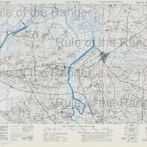 May include: A detailed map of Isigny, France, at a scale of 1:25,000. The map features intricate line work depicting roads, fields, and waterways, with blue lines highlighting rivers and canals. The text "FRANCE 1:25000" and "ISIGNY" are visible.