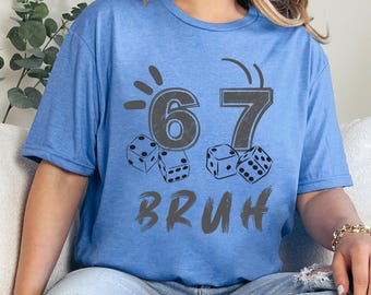 May include: A light blue t-shirt with a graphic design featuring the numbers "67", dice, and the word "BRUH" in gray. The shirt is a digital product.