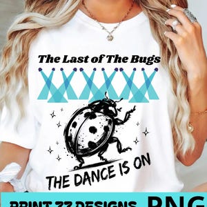 Peut inclure: Un t-shirt blanc avec une illustration en noir et blanc d'une coccinelle. Au-dessus de la coccinelle se trouvent six icônes de projecteurs bleus et le texte The Last of The Bugs. Sous la coccinelle, le texte THE DANCE IS ON. Des étoiles décorent.