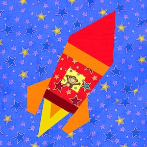 May include: A red, orange and yellow rocket ship with a monkey inside. The rocket is flying against a blue background with white stars.