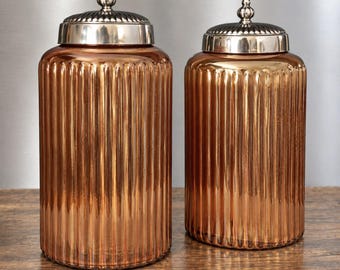 Zestaw 2 żebrowanych, pomarańczowych słoików aptecznych z ozdobnymi metalowymi pokrywkami, do przechowywania w kuchni w stylu mid-century vintage.