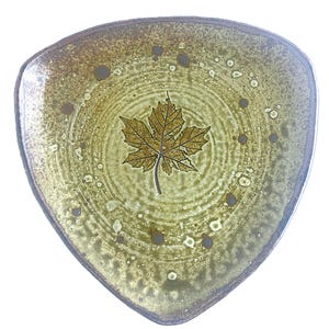 May include: Triangular ceramic plate with a leaf design. The plate features a light green and brown color scheme with a maple leaf in the center. The plate has a unique shape and a speckled texture.
