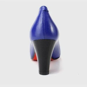 May include: A pair of blue high heels with a black heel and a red sole. The shoes are made of a smooth, shiny material and have a classic pump design. The heel is approximately 3 inches tall.