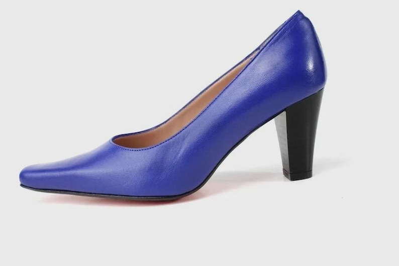 May include: A single blue leather pump with a pointed toe and a black block heel. The shoe has a low-cut vamp and a red sole. The heel is approximately 3 inches high.