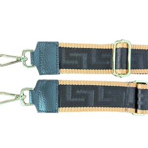 May include: Two black and tan bag straps with silver-tone metal clasps and hardware. The straps feature a geometric pattern and are designed for use with a purse or handbag. The straps are shown against a white background.
