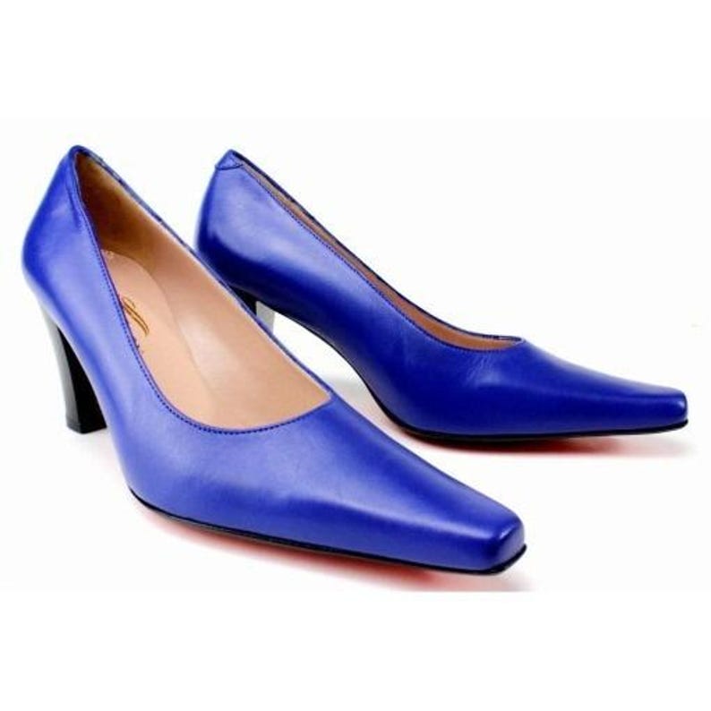 May include: A pair of cobalt blue high-heeled shoes with a pointed toe and a black heel. The shoes have a sleek, modern design, and the leather appears smooth and polished. The heels are approximately 3 inches tall.