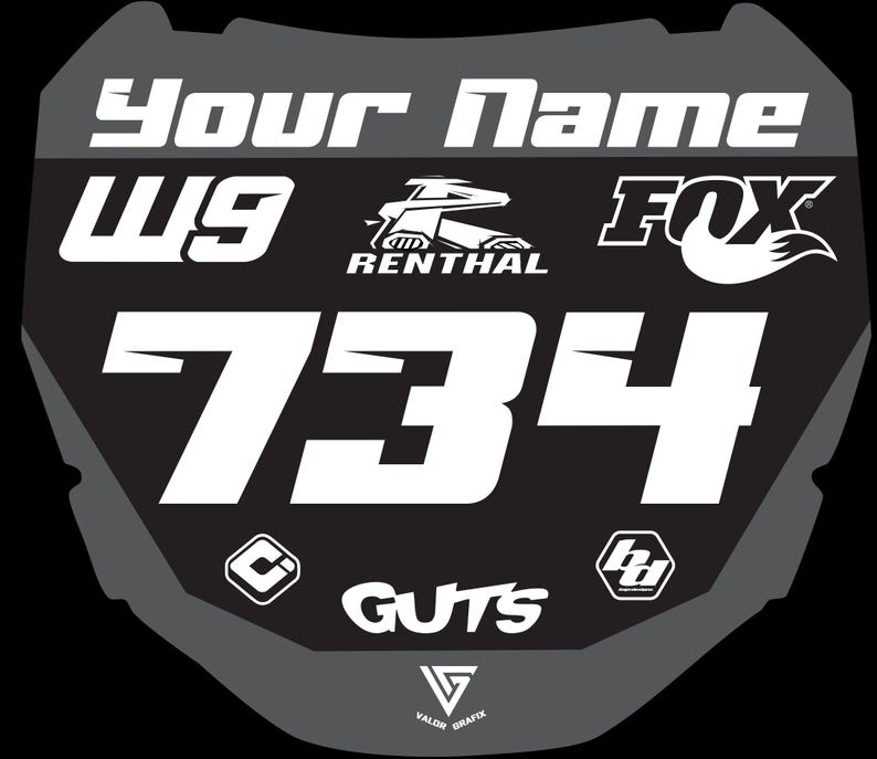 May include: A black and gray motocross number plate with the text "Your Name" at the top. The number "734" is prominently displayed in white, along with the logos for FOX, RENTHAL, and GUTS. Additional logos and the letters "W9" are also visible.