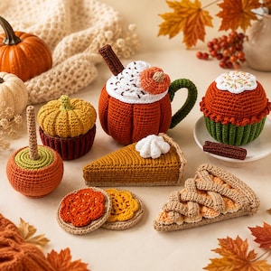 Op de afbeelding: Een verzameling gehaakte herfstitems, waaronder een pompoenmok met slagroom, een stuk pompoentaart, een stuk taart met een vlechtkorst, twee cupcakes, een karamelappel en twee ronde koekjes, uitgevoerd in oranje, bruine en groene garens.