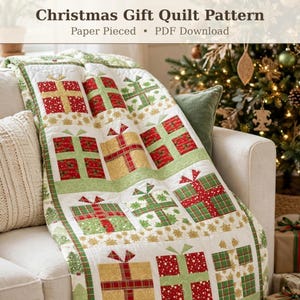 May include: A quilt featuring a repeating pattern of gift boxes in red, green, and gold fabrics with white borders. The text at the top reads Christmas Gift Quilt Pattern, Paper Pieced, PDF Download. The quilt is draped over a sofa.