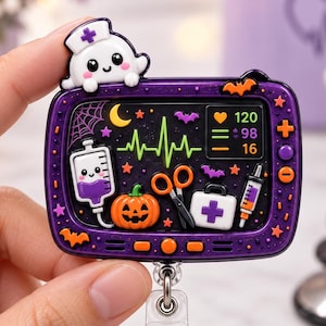 May include: A purple, television-shaped badge reel featuring a cute ghost nurse topper. The screen displays a heart rate monitor, a smiling IV bag, a jack-o'-lantern, scissors, a first aid kit, and a syringe, all accented with bats and stars.