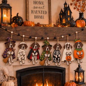 May include: A set of seven hanging wooden ornaments featuring spotted dogs in various Halloween costumes, including a witch, mummy, vampire, wizard, skeleton, ghost, and pumpkin, all suspended from a rustic twine string with black and white beads.