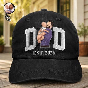 May include: Black baseball cap with the word "DAD" in white block letters, featuring an illustration of a father holding a baby. The text "EST. 2026" is below the word "DAD".
