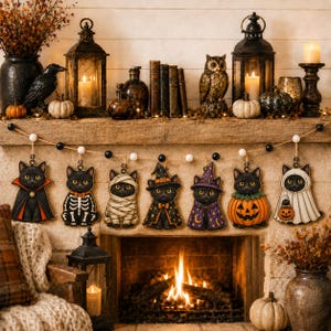 May include: A Halloween garland featuring seven hanging wooden ornaments of black cats in various costumes, including a vampire, skeleton, mummy, witch, wizard, pumpkin, and ghost, strung on a twine cord with alternating black and white beads.