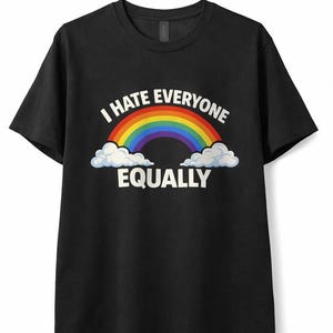 以下が含まれることがあります： 「I HATE EVERYONE EQUALLY」の文字と虹、白い雲のグラフィックがプリントされた黒いTシャツ。クルーネックのスタイルです。