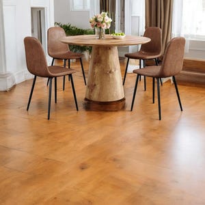 May include: A round wooden dining table with a pedestal base is surrounded by four brown upholstered chairs with black metal legs. A vase of flowers and a bowl of fruit sit on the table. The floor is made of wood.