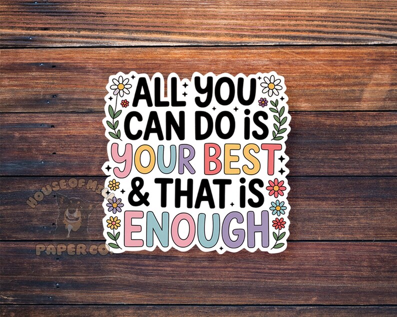 Puede incluir: Una pegatina colorida con el texto "ALL YOU CAN DO IS YOUR BEST & THAT IS ENOUGH". La pegatina tiene un borde blanco y est&aacute; decorada con flores y hojas. El fondo es una superficie de madera.