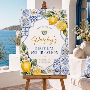 May include: A rectangular sign on a wooden easel featuring a white center with blue and yellow lemon and floral illustrations. Text reads: welcome to Paisley's BIRTHDAY CELEBRATION, Naples, FL, 09.20.2026. The border displays blue and white tile patterns.