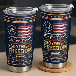 May include: Two navy blue stainless steel tumblers with clear lids, featuring a distressed American flag, gold stars, and the text "We the People 250 YEARS OF FREEDOM" with the name "Jonathan" and the years "1776 2026" printed in gold lettering.