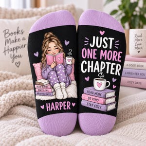 May include: A pair of black socks with lavender cuffs and heels. The left sock features an illustration of a person reading a book with the name Harper below. The right sock displays the text Just One More Chapter above a stack of books and a mug.
