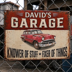 May include: A rectangular metal sign with a distressed finish featuring the text DAVID'S GARAGE at the top and KNOWER OF STUFF FIXER OF THINGS at the bottom. In the center is a graphic of a red vintage station wagon car with chrome details.