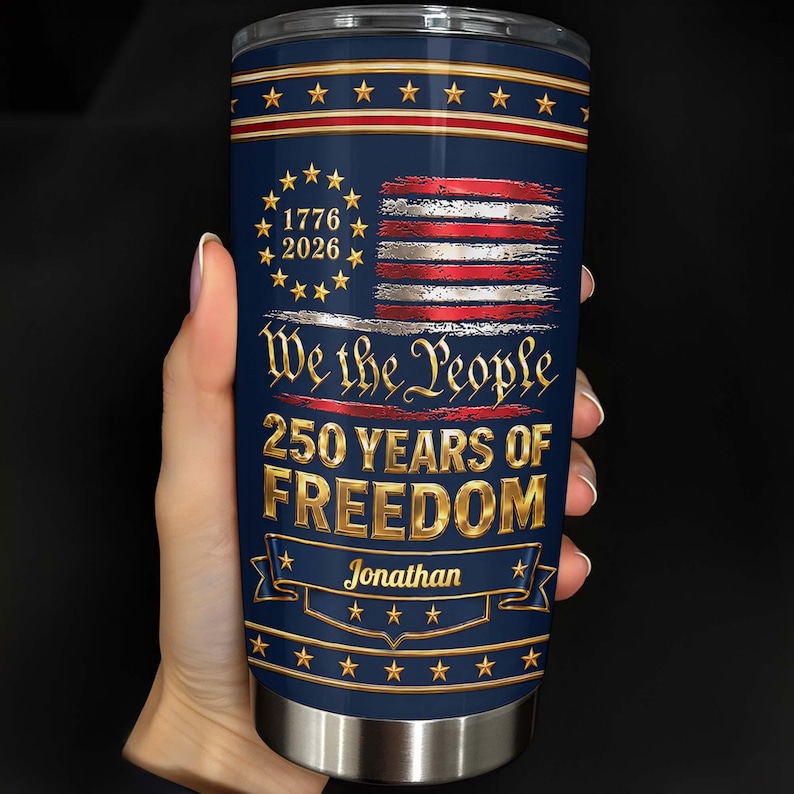 May include: A cylindrical stainless steel tumbler with a dark blue background featuring a distressed American flag, gold stars, and the text 1776 2026, We the People, 250 YEARS OF FREEDOM, and the name Jonathan printed in a gold banner at the bottom.