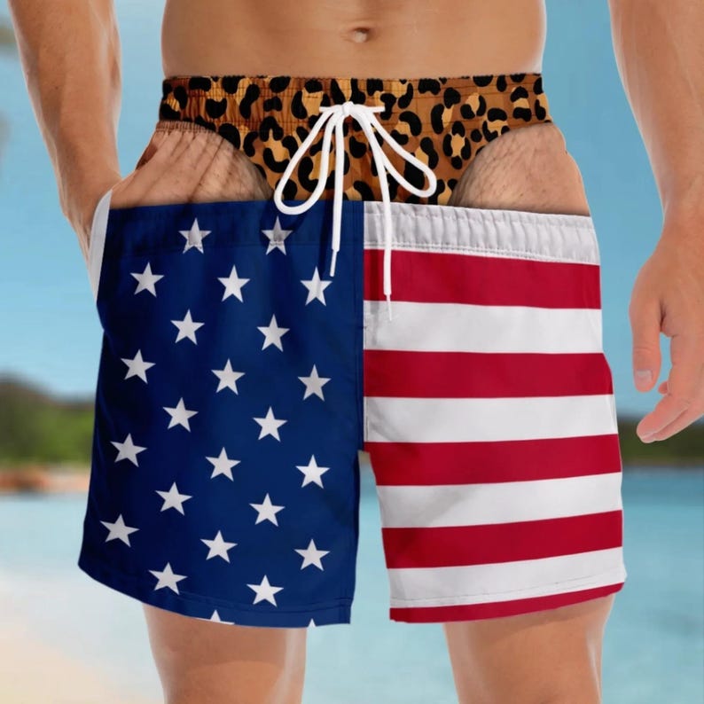 May include: Swim trunks featuring a split design with a blue field of white stars on the left and red and white horizontal stripes on the right. The waistband displays a brown and black leopard print pattern and includes a white drawstring cord.