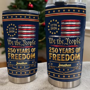May include: Two navy blue stainless steel tumblers with lids, featuring a graphic of the American flag, the text 1776 2026, We the People, 250 YEARS OF FREEDOM, and the name Jonathan printed in gold lettering on a decorative banner design.