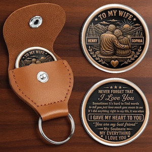 May include: A tan leather keychain pouch with a silver snap button containing a round metal coin. The coin features a relief of a couple with the text TO MY WIFE, HENRY, and SOPHIA. The reverse side displays the text NEVER FORGET THAT I LOVE YOU.