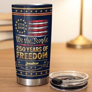 May include: A navy blue stainless steel tumbler featuring a patriotic design with a distressed American flag, the text 1776 2026, We the People, 250 YEARS OF FREEDOM, and the name Jonathan. The tumbler includes a clear plastic lid with a black slider.