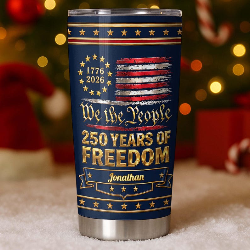 May include: A navy blue stainless steel tumbler featuring a gold and red American flag design with a circle of stars, the text 1776 2026, We the People, 250 YEARS OF FREEDOM, and the name Jonathan printed in gold lettering on a banner.
