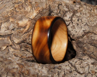 Puede incluir: Un anillo de madera con un borde exterior marrón oscuro y un borde interior marrón claro. El anillo está hecho de madera y tiene un acabado natural.