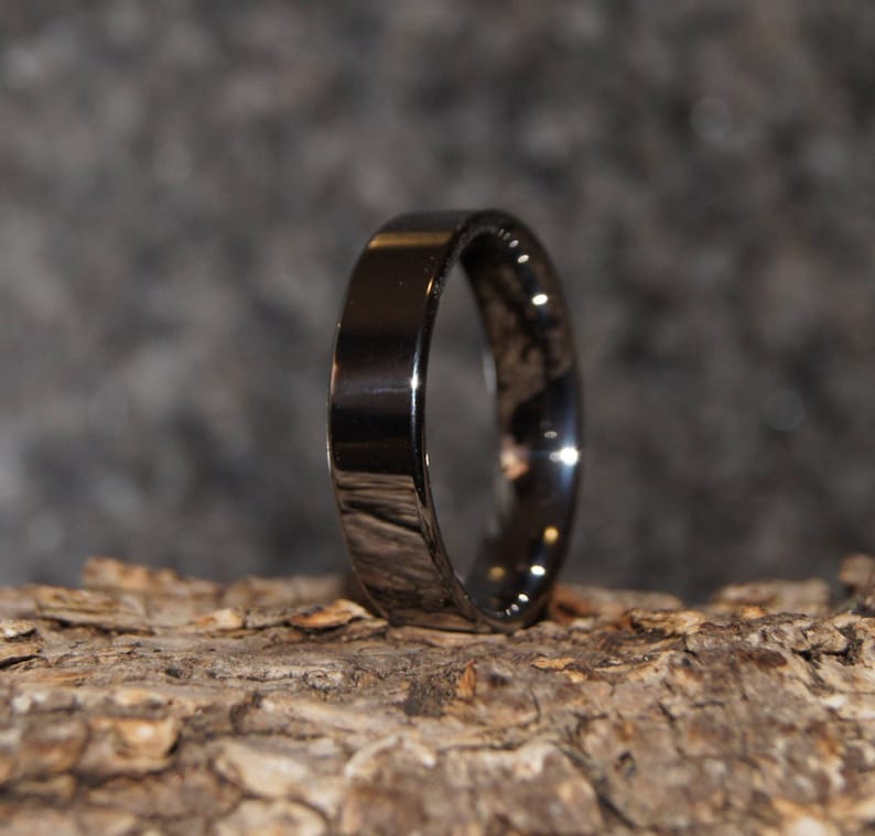 May include: A black ring with a polished finish. The ring is made of a durable metal and has a simple, modern design.