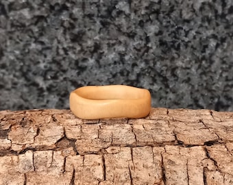 Puede incluir: Un anillo de madera simple, de color marrón claro, con una superficie lisa y redondeada.