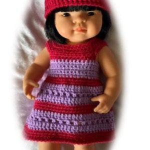 May include: A doll wearing a purple and red striped crocheted dress and a matching crocheted hat.