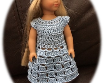May include: A blue crocheted dress and hat set for a doll. The dress has a square pattern and the hat is a simple beanie style.