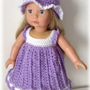 May include: A purple crocheted dress with white trim and a matching purple crocheted hat with white trim. The dress has a scalloped hemline.