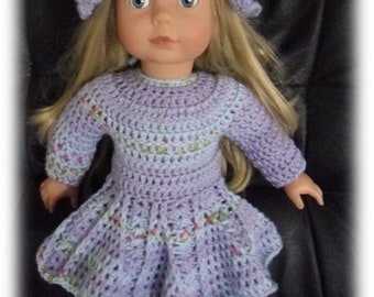 May include: A crocheted doll dress and hat set in shades of purple and blue with a flower embellishment on the hat.