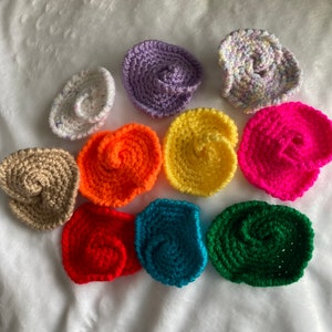 May include: Ten crocheted flower shapes in various colors, including purple, yellow, pink, red, green, and brown. The flowers are all about 3 inches in diameter and have a spiral design.