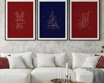 Może przedstawiać: Trzy oprawione grafiki świąteczne. Każda z nich przedstawia geometryczny wzór: renifera, choinkę ze słowem "JOY" i skarpetę. Tła są czerwone i granatowe. Grafiki wiszą nad białą sofą.