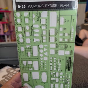 May include: A light green Berol Rapidesign R-26 plumbing fixture plan template featuring various cutouts for architectural drafting. The plastic sheet includes labels for lavatories, water closets, sinks, and hospital products with printed dimensions.